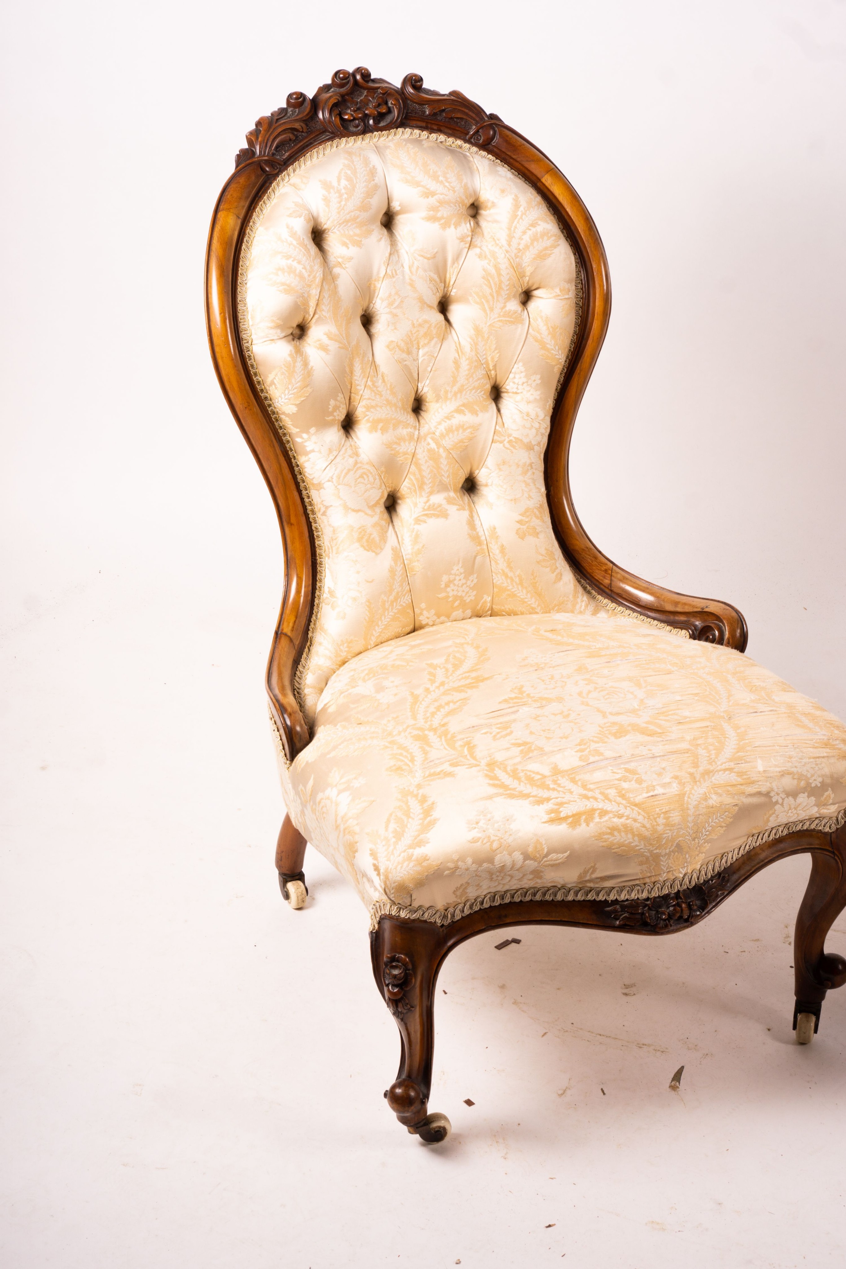 A late Victorian carved walnut three piece salon suite, comprising chaise longue, open armchair and nursing chair